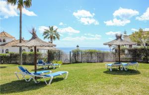 een groep stoelen en parasols op het gras bij 2 Bedroom Amazing Apartment In Manilva in Manilva