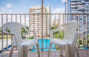 two white chairs on a balcony with a pool at 1 Bedroom Awesome Apartment In Puebla De Farnals in Puebla de Farnals