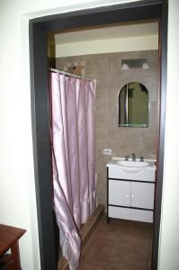baño con lavabo y cortina de ducha rosa en El Rincón del Molle en Merlo