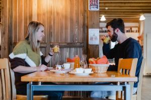 een man en een vrouw die aan een tafel sap drinken bij Hotel Cornelyshaff in Heinerscheid