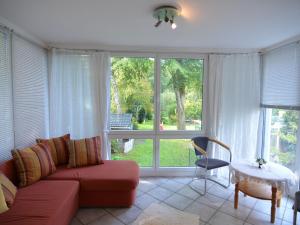 a living room with a red couch and a table and window at Luxurious Apartment in Sch now with Sauna in Bernau bei Berlin