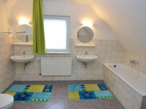 uma casa de banho com 2 lavatórios, uma banheira e 2 espelhos em Nice holiday home near ski area em Medebach