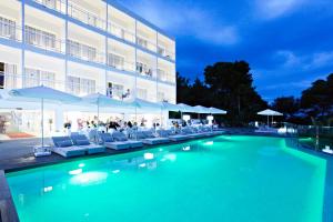 a swimming pool in front of a hotel with chairs and umbrellas at Grupotel Ibiza Beach Resort - Adults Only in Portinatx