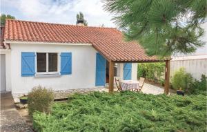 een klein wit huis met blauwe luiken bij Cozy Home In La Tranche-sur-mer With Kitchenette in La Tranche-sur-Mer