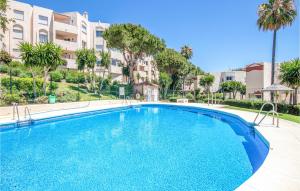 a swimming pool in a apartment with palm trees and buildings at Nice Apartment In Rivera Del Sol in La Cala de Mijas +23 photos