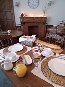 uma mesa de madeira com pratos e copos e um relógio em La Belle Vienne em Exideuil
