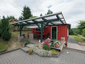 a red shed with a pergola and a bench at Detached holiday home in the Harz with wood stove in Güntersberge