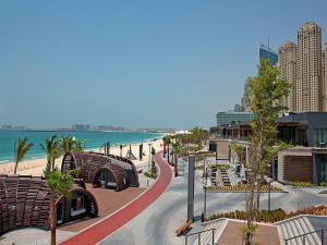 a street with benches and the beach and buildings at 2 Bedroom Apartment - JBR in Dubai