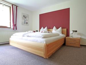 a bedroom with a large bed with a red wall at Charming Apartment with Balcony Garden BBQ Parking Heating in Schmallenberg