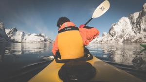a person in a kayak on a body of water at Catogården - Boutique Home & Activity Centre in Reine
