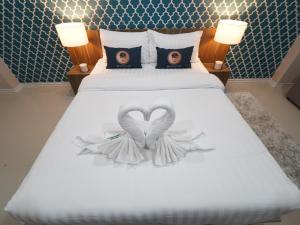 una cama con dos alas blancas y dos fotos en ella en RoomQuest Rojana Industrial Estate area en Ban Nong Phai