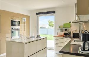 a kitchen with white cabinets and a large window at Awesome Home In St,germain-ay-plage With 3 Bedrooms And Wifi in Saint-Germain-sur-Ay