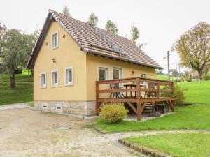a small yellow house with a large wooden deck at Charming Holiday Home in Hohnstein ot Lohsdorf in Hohnstein