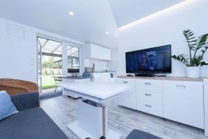 a white living room with a white table and a tv at Domy Rafa Ustka in Ustka