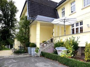 a yellow house with an umbrella in the driveway at Villa with a view of the Weserbergland in Bad Pyrmont