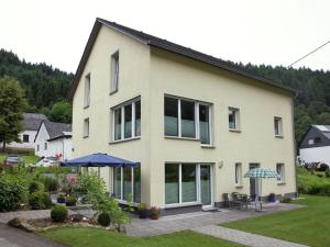 a house with a patio and an umbrella at Apartment with terrace and view in Merschbach
