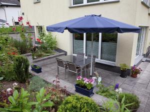 a table with a blue umbrella in a garden at Apartment with terrace and view in Merschbach
