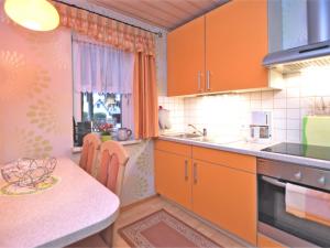kuchnia z pomarańczowymi szafkami i małym stołem w obiekcie Vintage Holiday Home in Trieb with Terrace w mieście Trieb