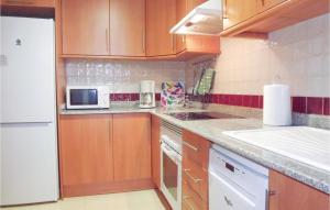 a kitchen with wooden cabinets and a white microwave at Nice Apartment In Denia With Wifi in Denia +10 photos