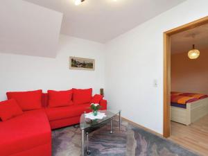 un soggiorno con divano rosso e letto di Mountain view Apartment in Mullenborn Garden a Gerolstein