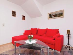 un divano rosso in soggiorno con tavolo in vetro di Mountain view Apartment in Mullenborn Garden a Gerolstein