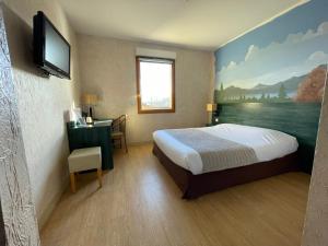 Habitación de hotel con cama y TV de pantalla plana. en La Tour D'ivoire, en Reignier