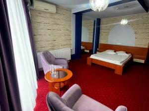 een kamer met een bed, een bank en stoelen bij Hotel SunGarden Salin in Turda