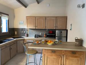 a kitchen with wooden cabinets and a bowl of fruit on a counter at Maison Vert d'Eau in Grand-Village-Plage