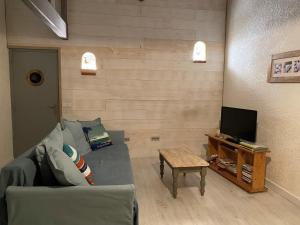 een woonkamer met een bank en een tv bij Maison Vert d'Eau in Grand-Village-Plage