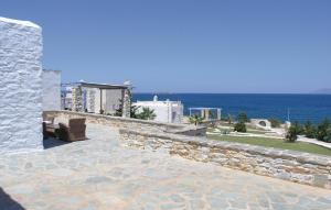 a patio with a stone wall next to the ocean at Amazing Home In Ampela, Paros With 3 Bedrooms And Wifi in Isterni