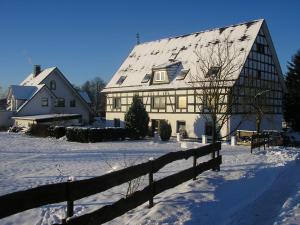 una gran casa blanca en la nieve con una valla en Apartment with panoramic views, en Attendorn