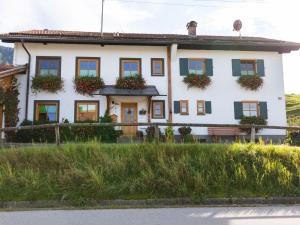 a white house with flowers on the windows at Apartment near the Halblech ski resort in Trauchgau