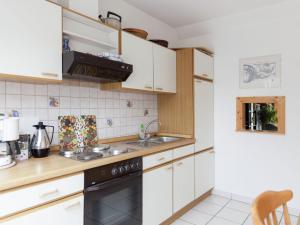 a kitchen with white cabinets and a black dishwasher at Pleasing Apartment in Traben Trarbach with Balcony in Wolf