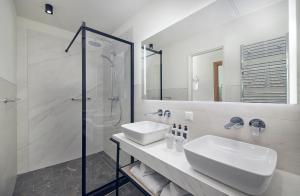 a white bathroom with a sink and a shower at Hotel New York by WestCord in Rotterdam