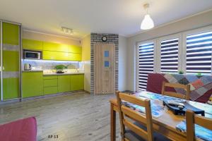 comedor y cocina con armarios verdes y mesa en Apartament Luba, en Krynica Morska