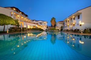 a swimming pool in front of buildings at night at Acrotel Lily Ann Village in Nikiti