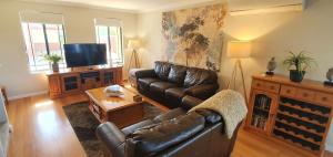 a living room with a leather couch and a tv at Palm Beach Manor in Rockingham