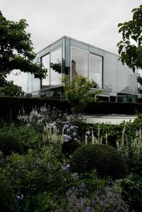 a glass house with a garden in front of it at H-House Architectural Residence in Maastricht +26 photos