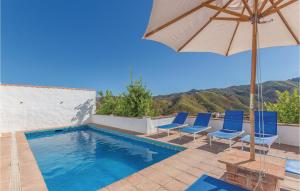 una piscina con sillas azules y sombrilla en Stunning Home In Almachar With 5 Bedrooms, Wifi And Outdoor Swimming Pool, en Almáchar