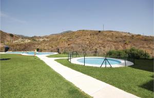dos piscinas en un parque con una colina al fondo en Amazing Apartment In Fuengirola-carvajal With 2 Bedrooms, Wifi And Outdoor Swimming Pool, en Santa Fe de los Boliches
