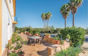 eine Terrasse mit einem Tisch, Stühlen und Palmen in der Unterkunft 6 Bedroom Cozy Home In Huelva in Huelva