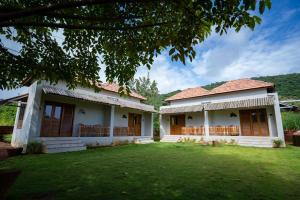 a house with a lawn in front of it at the woodland retreat in Dapoli