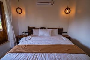 a bedroom with a large bed with two lights at the woodland retreat in Dapoli