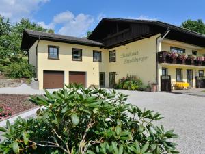 een groot geel huis met een zwart dak bij Holiday home with sauna near a ski resort in Drachselsried