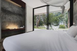 a bedroom with a large white bed and a large window at Costa Lanta - Adult Only in Ko Lanta