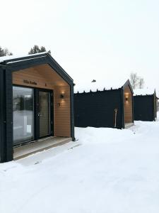 un bâtiment noir et en bois dans la neige dans l'établissement Willa Rauha F, à Lumijoki