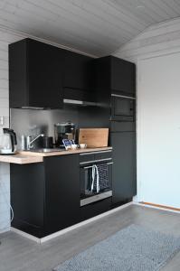 a kitchen with black cabinets and a stove at Willa Rauha F in Lumijoki