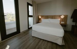 a bedroom with a white bed and a large window at Petit Palace Vargas in Seville