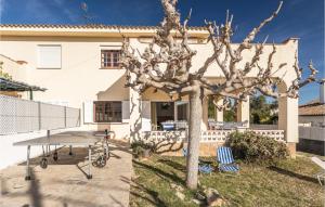 un árbol con dos sillas y una mesa frente a una casa en Roc De San Gaiet, en Comarruga