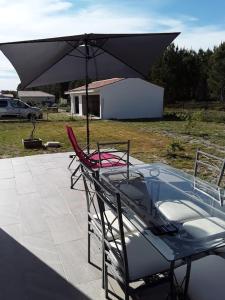 a table with an umbrella and a chair on a patio at Villa en bordure de forêt . in Onesse-et-Laharie